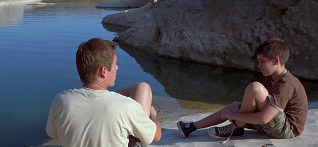 Movie Still of Man and Boy talking while sitting beside the falls