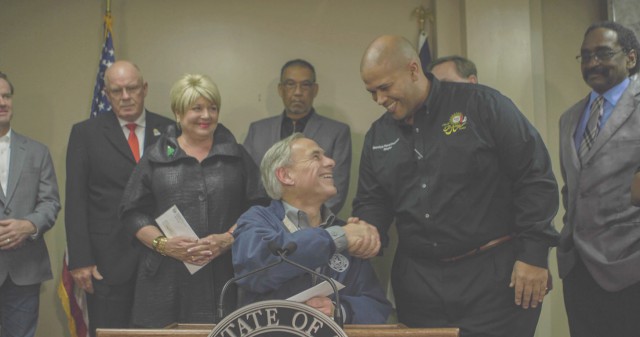 Governor Abbott shakes the hand of local official and presents funds for debris removal.
