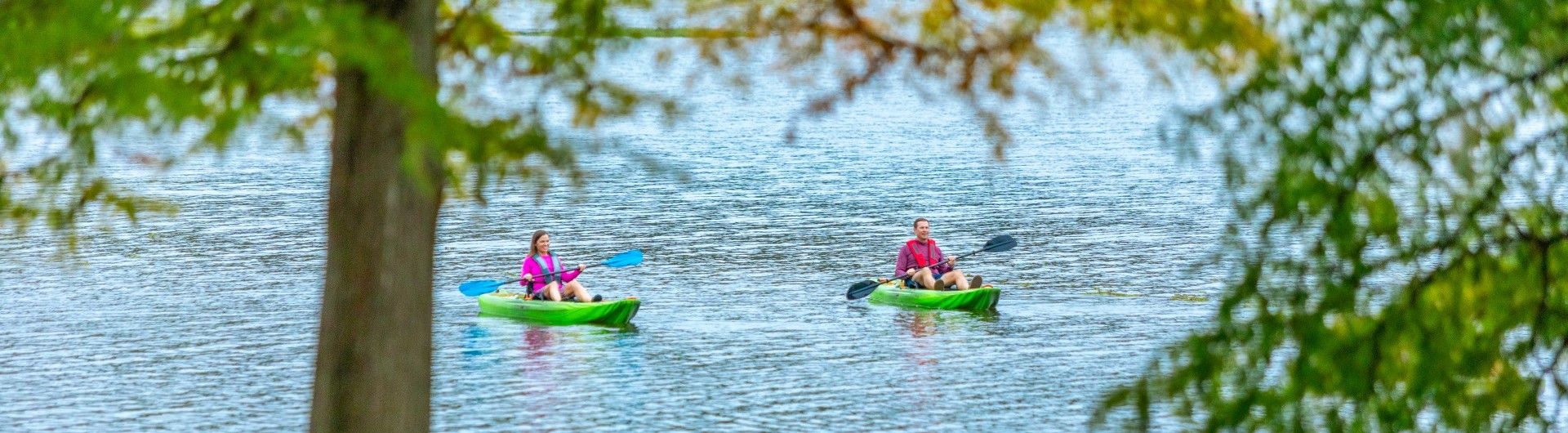 a couple kayaking on a lake with woods surrounding